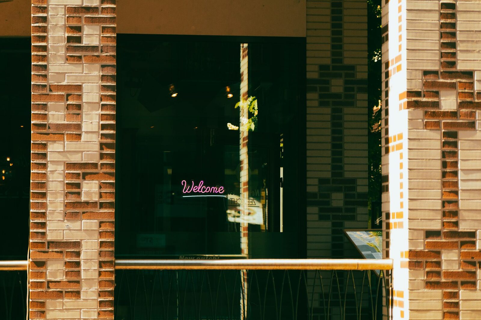 Stylish neon 'Welcome' sign on an urban brick facade with a modern aesthetic.