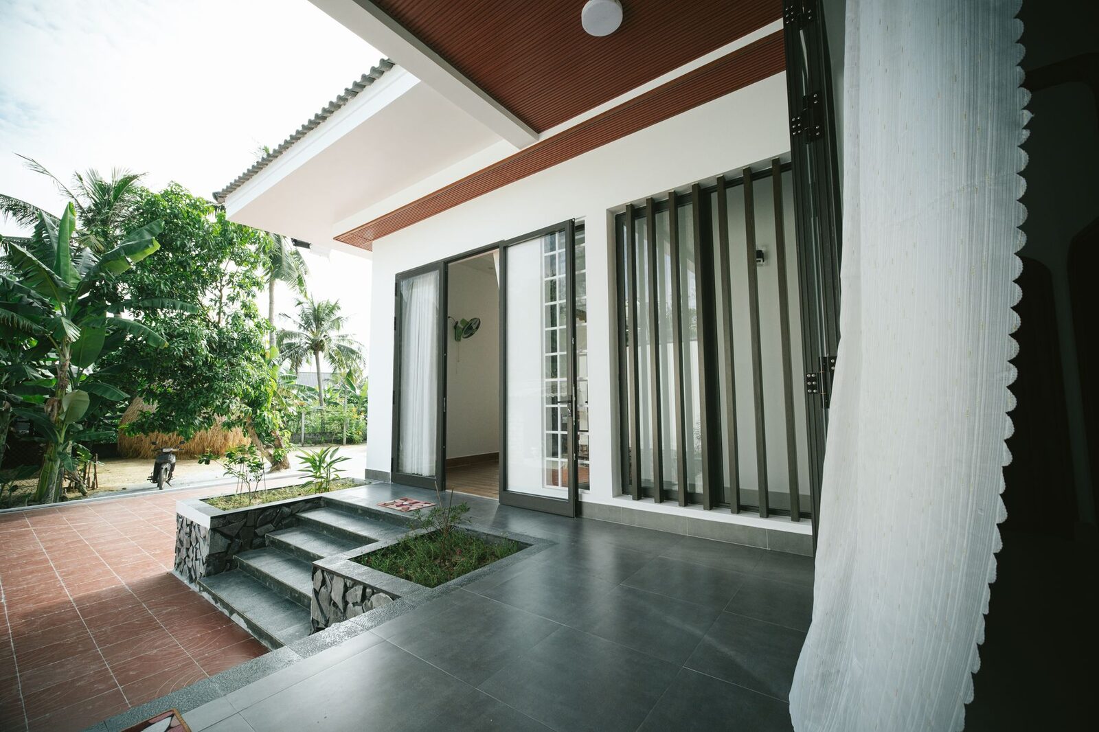 A contemporary house featuring a spacious outdoor patio and lush garden in daylight.