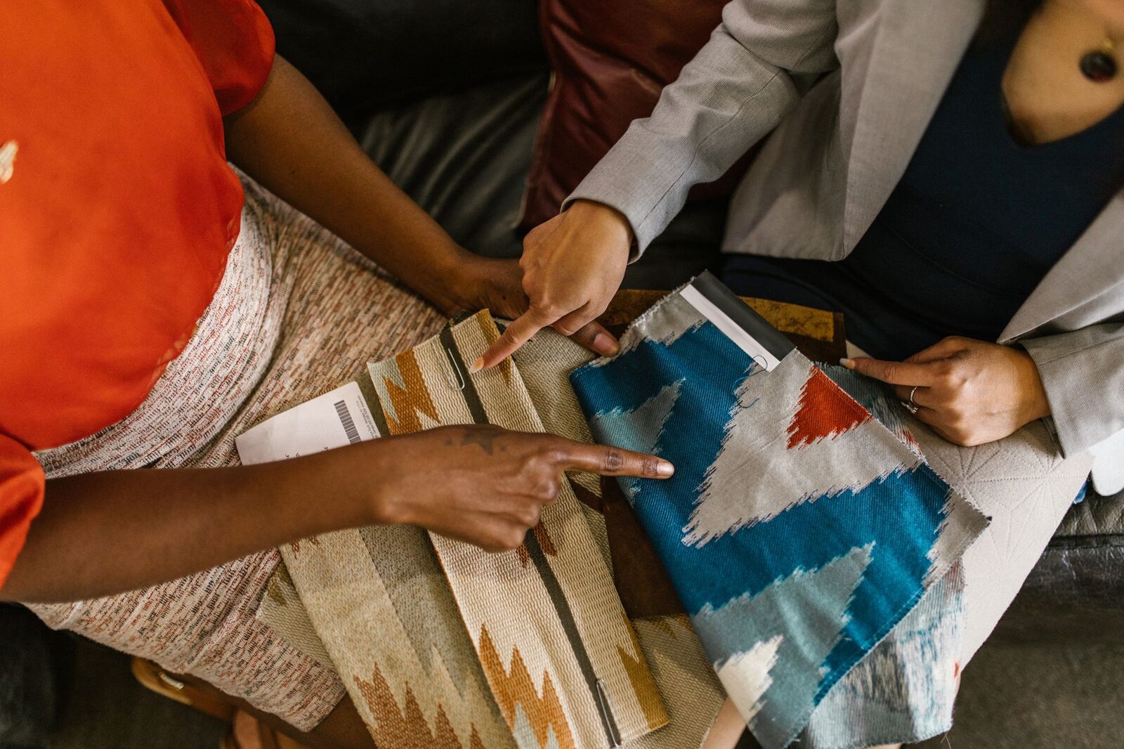 Two professionals assessing colorful fabric swatches for interior design project.