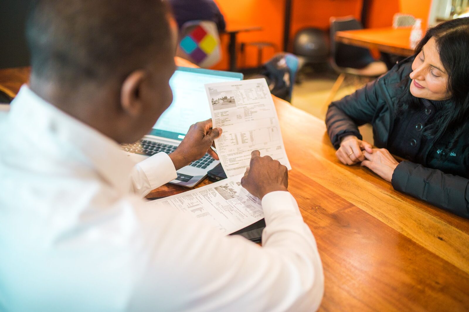 Two adults discussing documents in a business setting indoors.